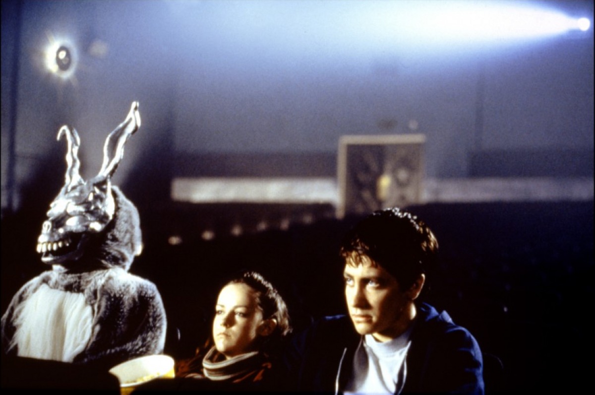 two teenagers and someone in a scary rabbit costume, sitting in a cinema